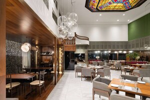 Un restaurante espacioso con techos altos, un techo de vidrieras y una variedad de zonas de comedor.