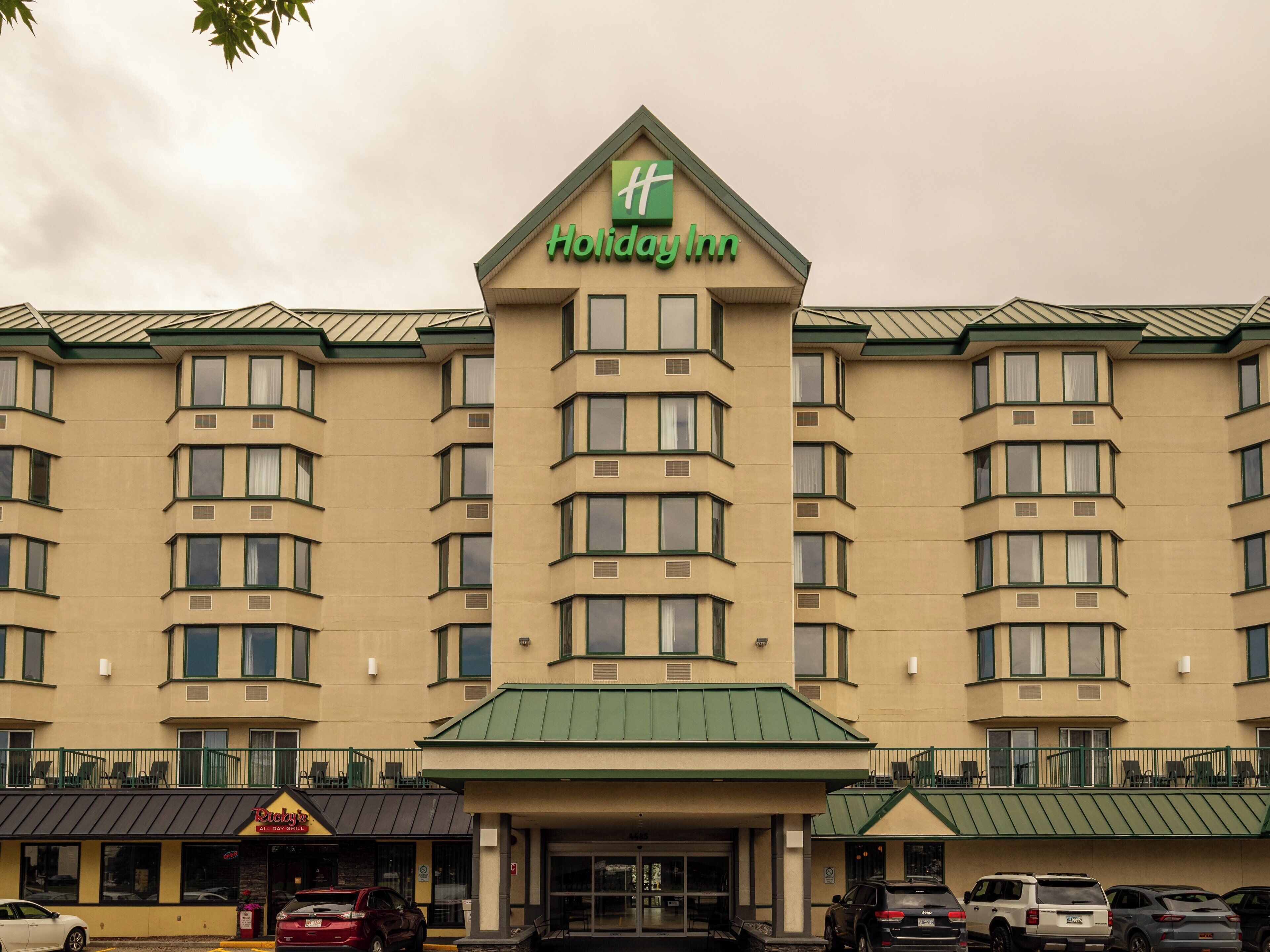 A Holiday Inn hotel with a symmetrical facade, multiple windows, and a green roof.