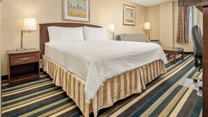 A hotel room with a large bed, two bedside tables with lamps, a chair, a desk, and a window with curtains. - Holiday Inn Conference Center Edmonton South by IHG (Edmonton)