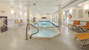 Zona de piscina con jacuzzi, asientos y señalización de salida.