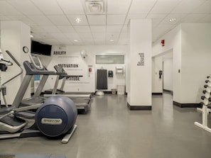 Une salle de sport équipée de tapis de course, d’un vélo elliptique et d’un vélo d’appartement.