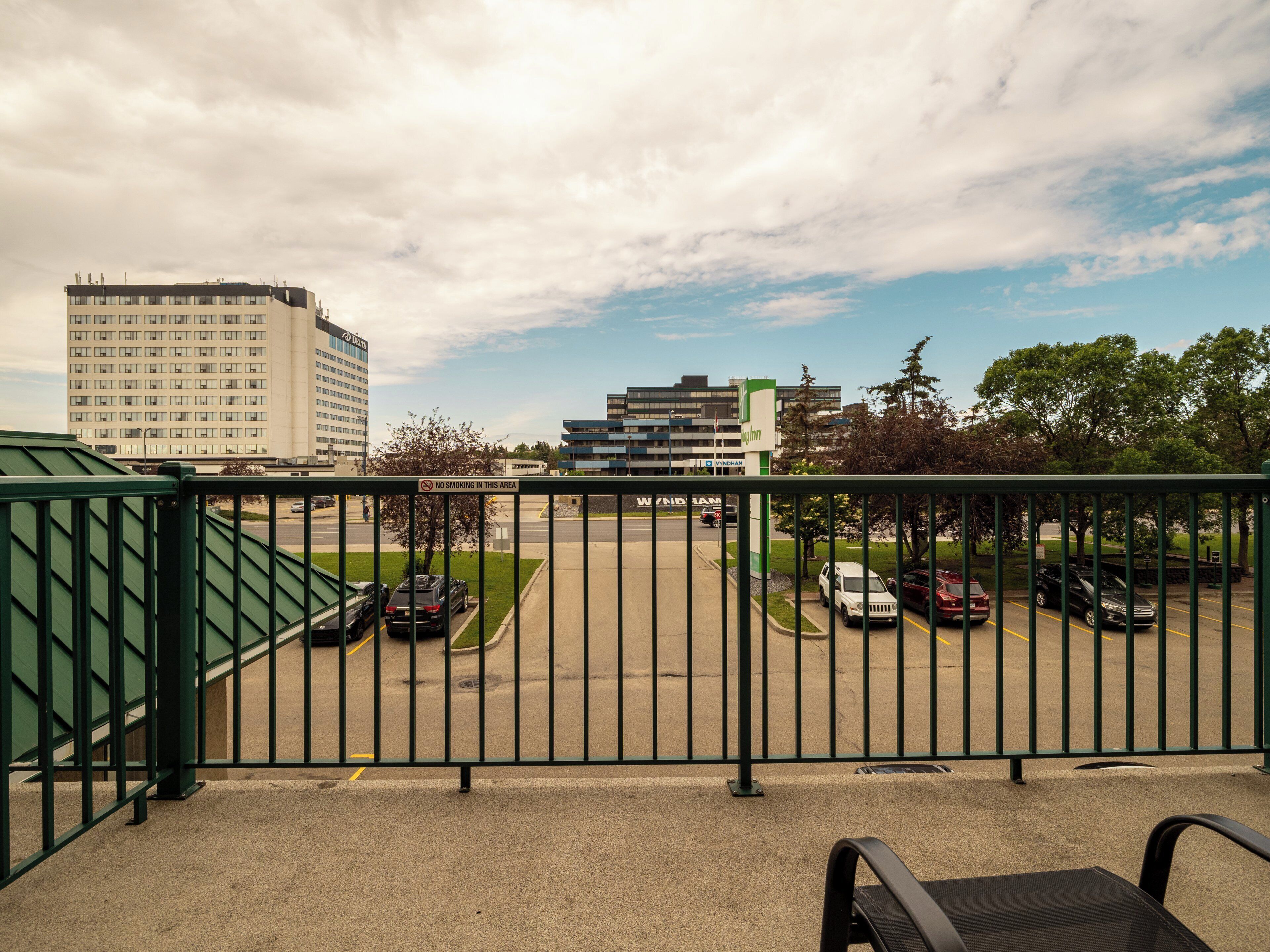 A balcony with a view of a parking lot and buildings.