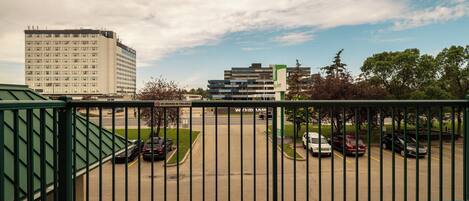 A balcony with a view of a parking lot and buildings.