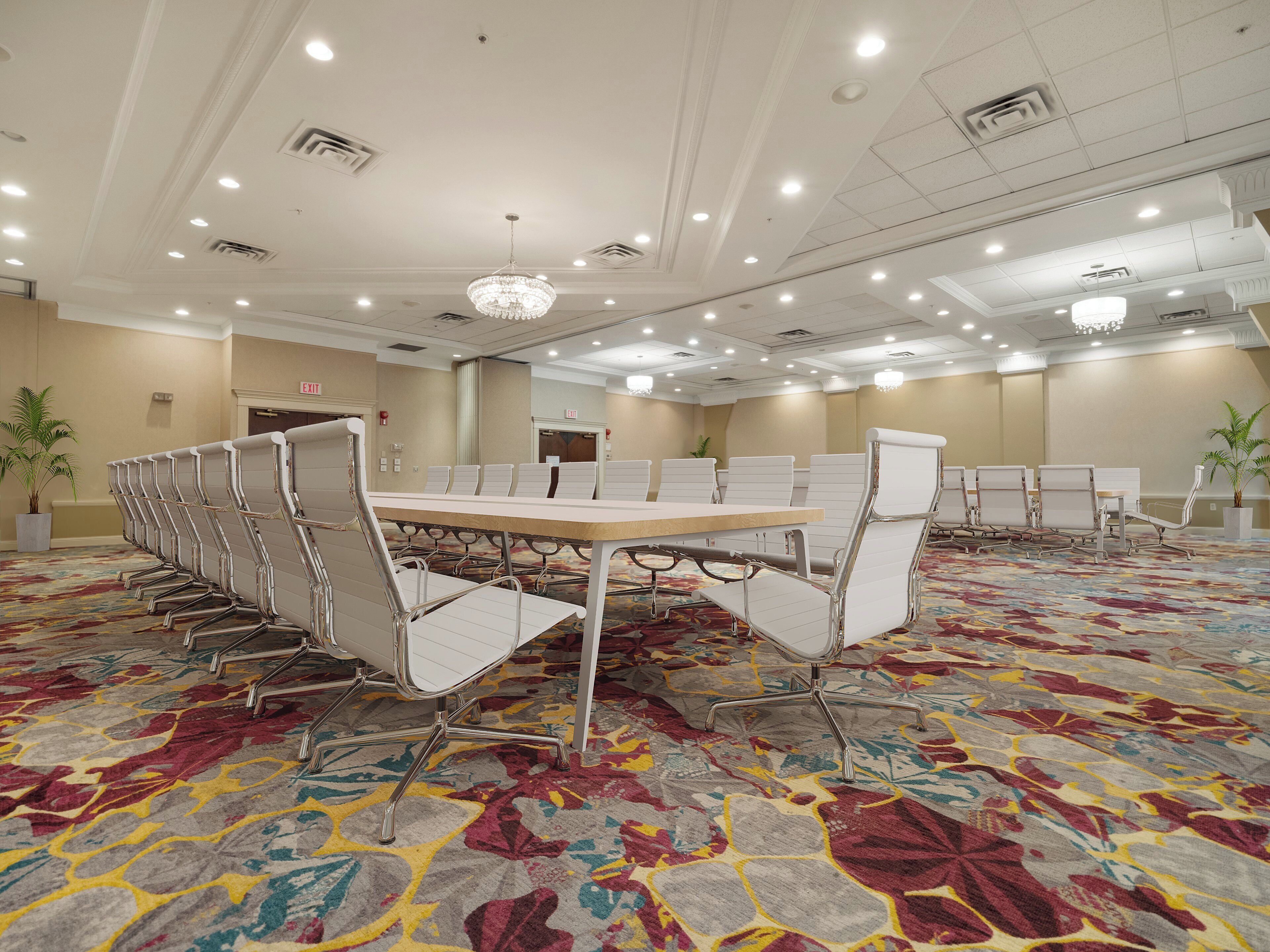 A conference room with a long table and chairs, carpeted floor, and ceiling lights.