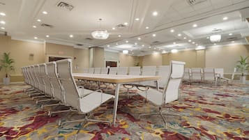 A conference room with a long table and chairs, carpeted floor, and ceiling lights.