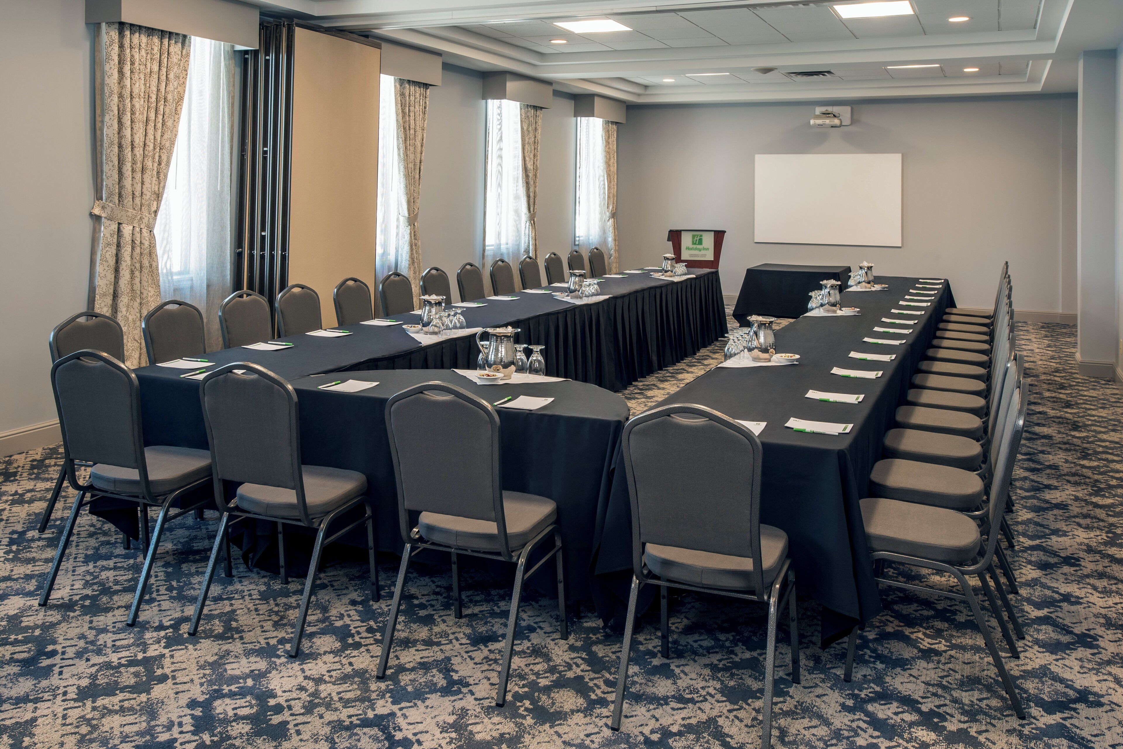 A conference room with a long table, chairs, and a podium.
