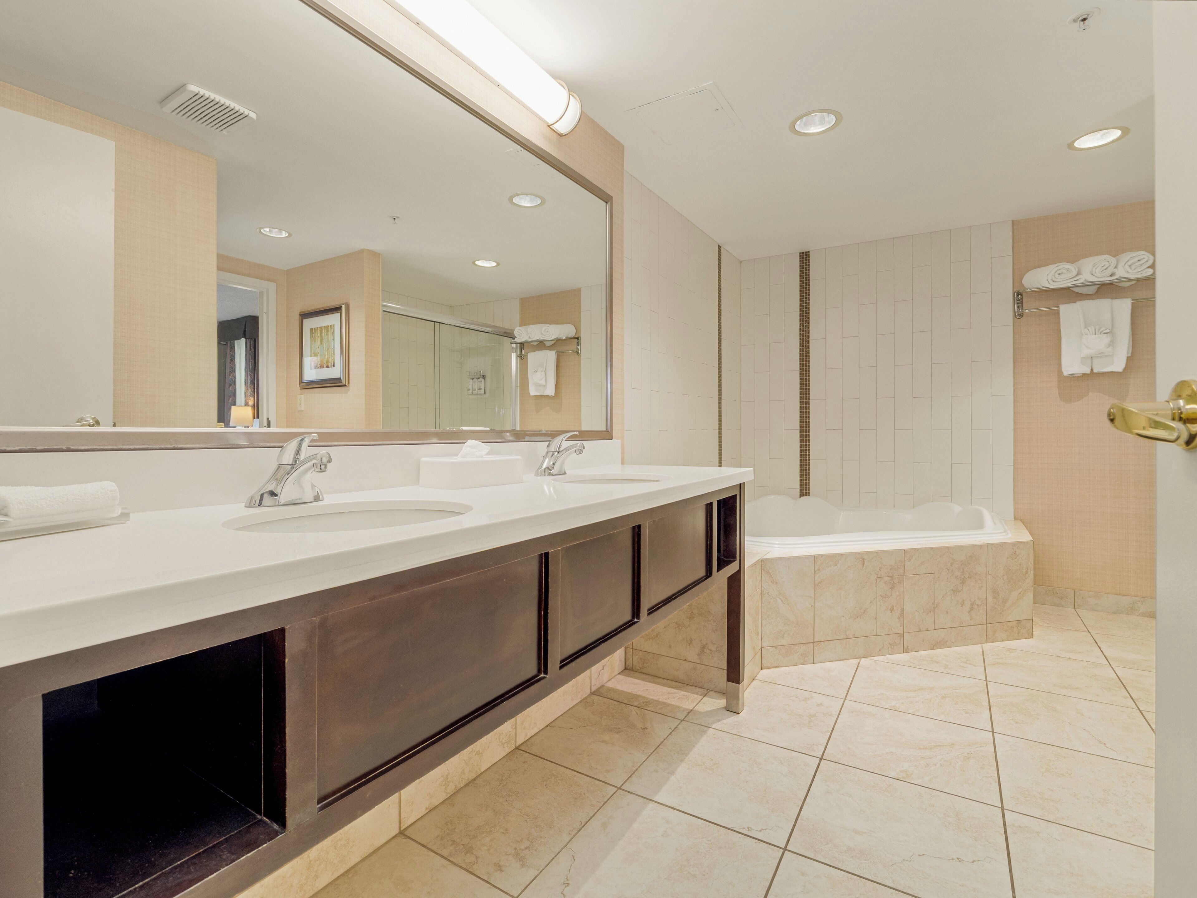 Une salle de bain moderne avec un meuble-lavabo à deux vasques, un grand miroir, une baignoire et un espace douche.