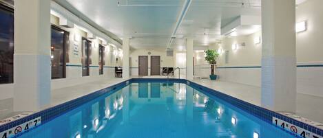 An indoor swimming pool with clear lane markings, a lifeguard chair, and a sign indicating no lifeguard on duty.