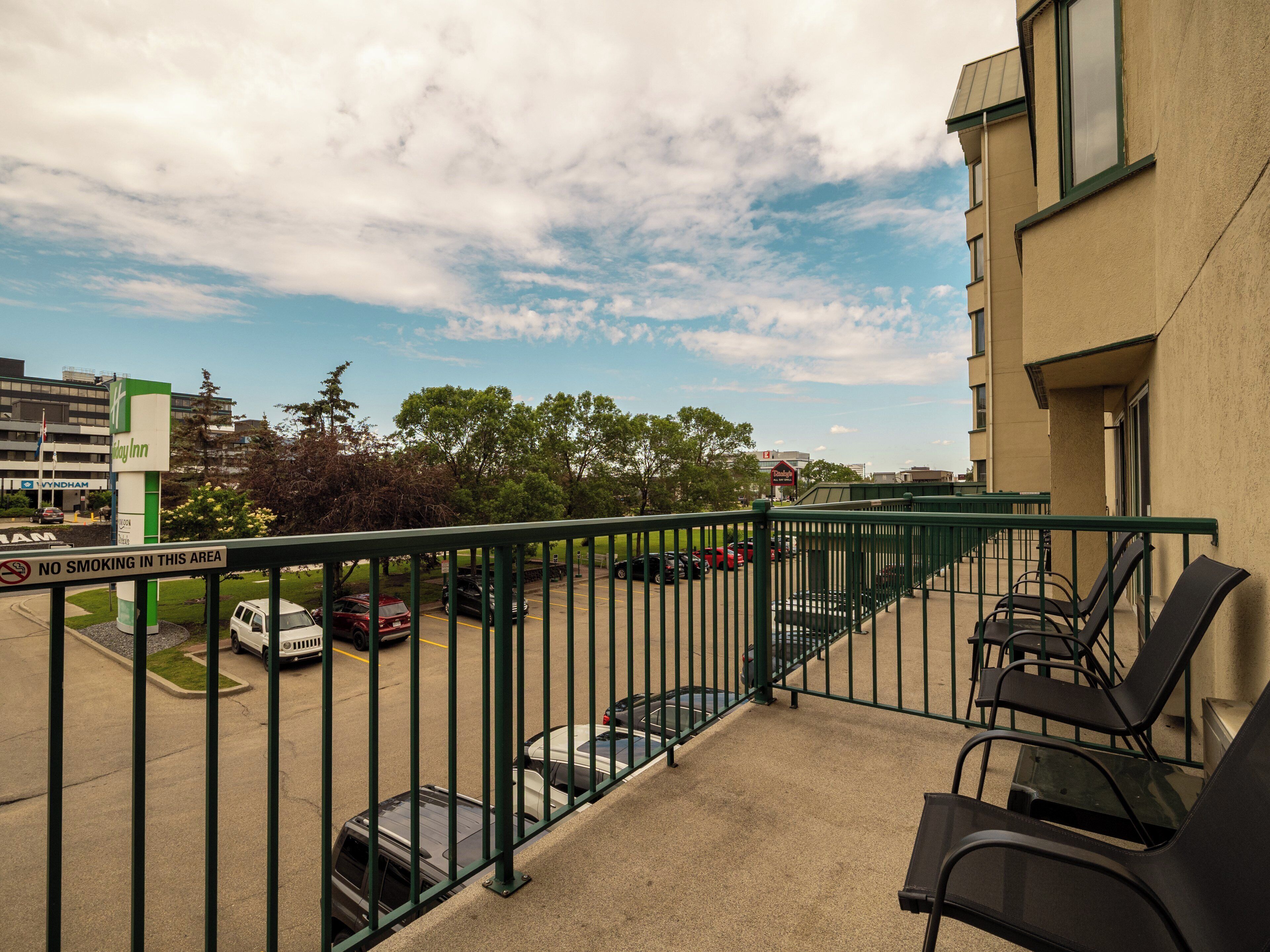 Un balcon d’hôtel donnant sur un parking, une enseigne d’un hôtel Holiday Inn Express et un panneau indiquant qu’il est interdit de fumer.