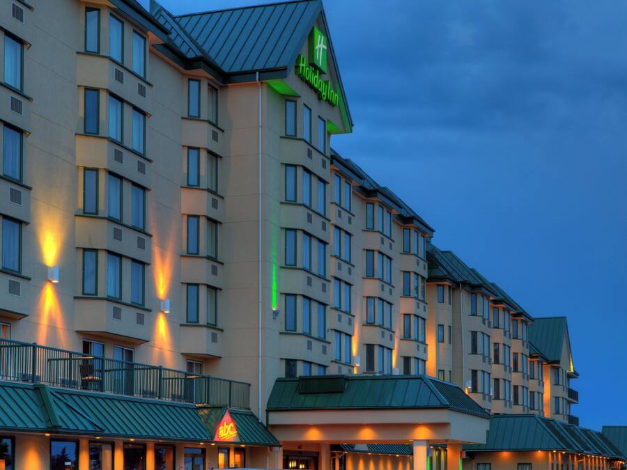 A multi-story hotel building with a green roof and a prominent green sign indicating it is a Holiday Inn.