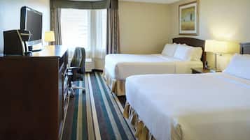 A hotel room with two beds, a desk with a computer, a chair, and a TV.