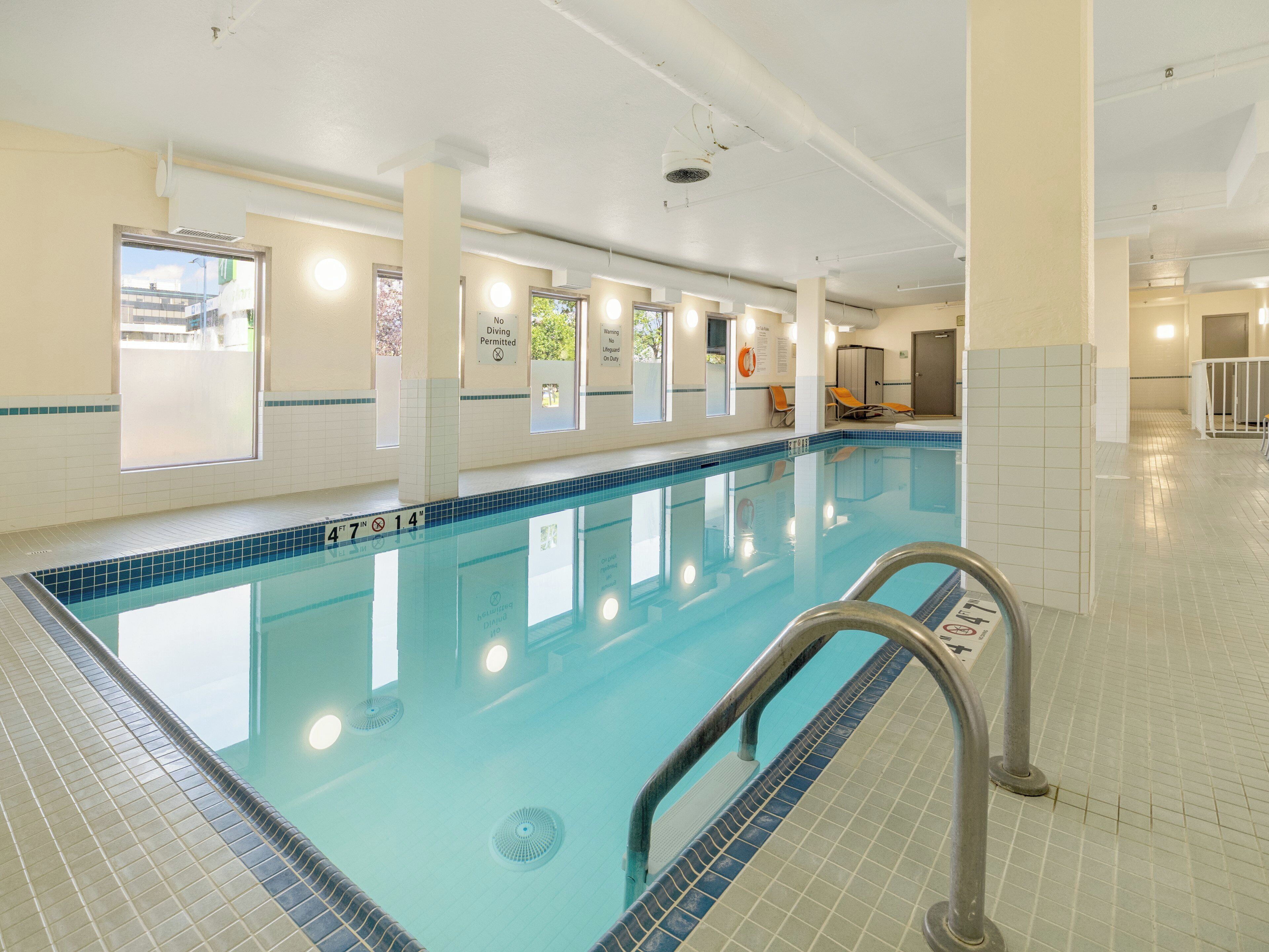 An indoor swimming pool with clear water, tiled walls, and a no diving sign.