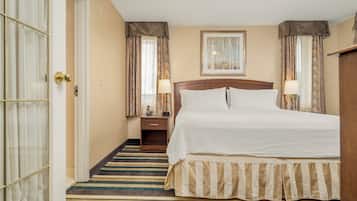 Habitación de hotel con una cama grande, una mesita de noche con lámpara, un cuadro enmarcado en la pared y una alfombra a rayas.