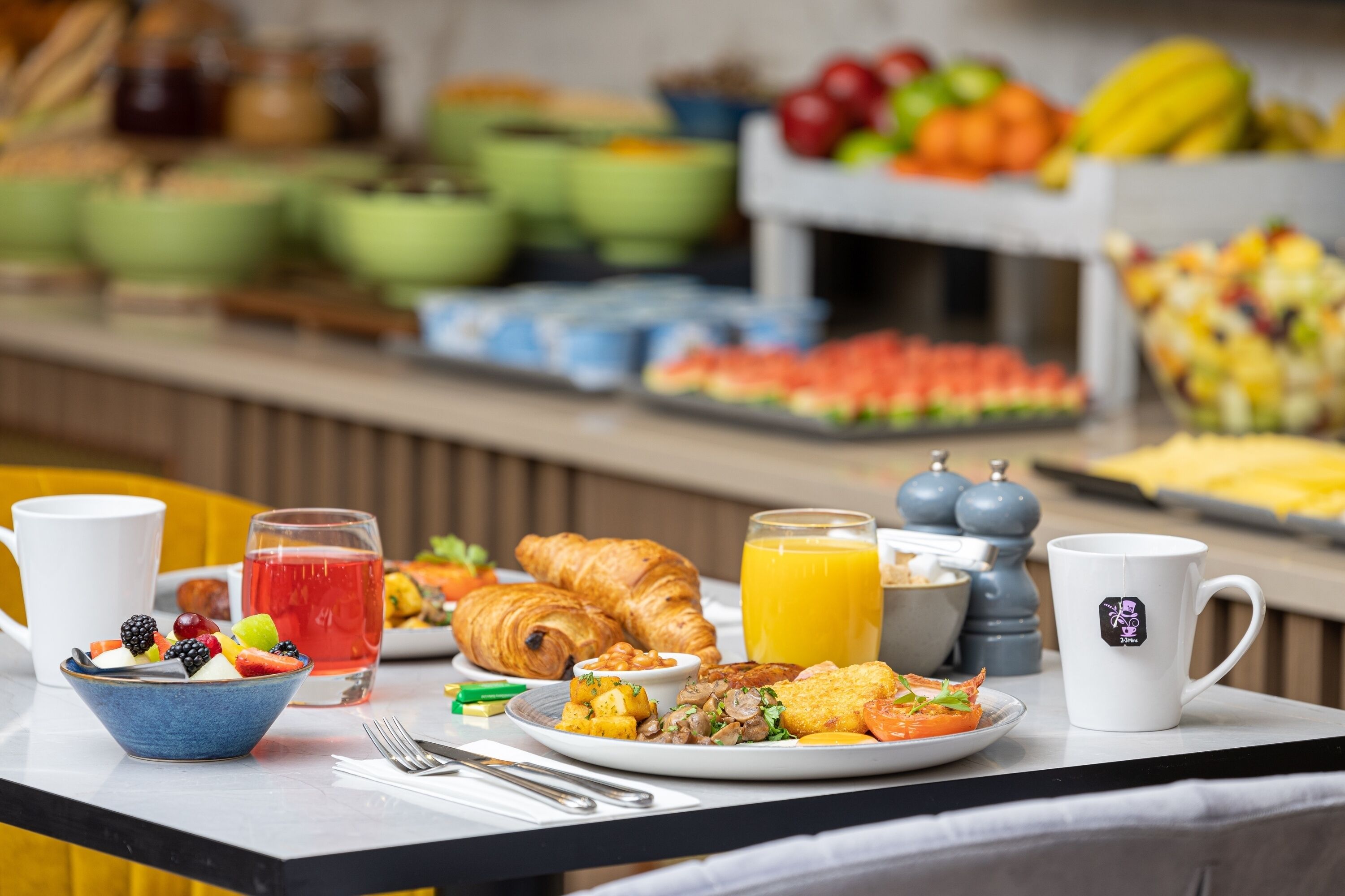 Un ricco buffet della colazione con diverse pietanze, tra cui frutta, pasticcini e bevande.