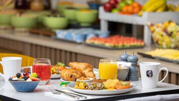 Un ricco buffet della colazione con diverse pietanze, tra cui frutta, pasticcini e bevande.