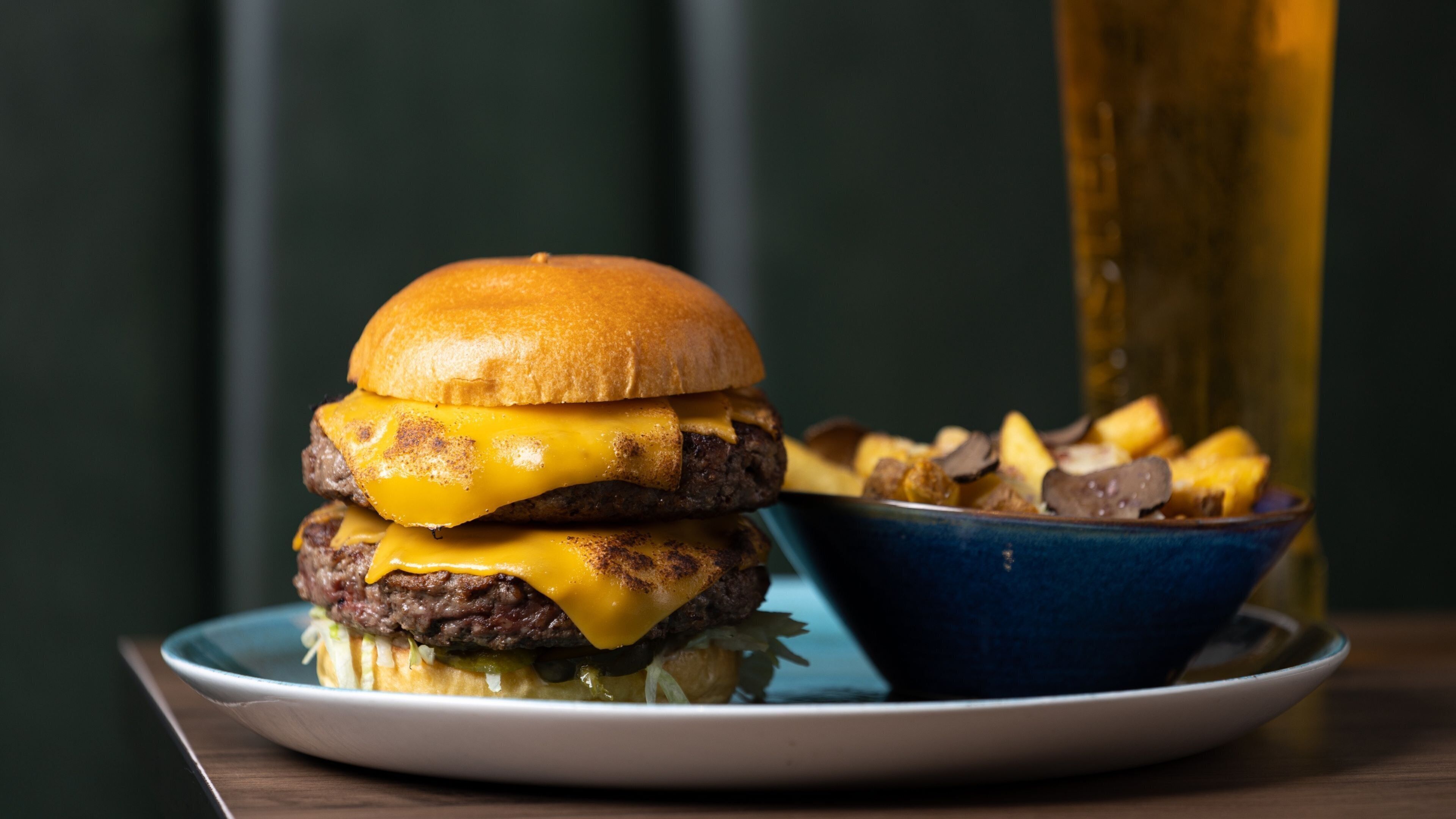 Ein Burger mit Käse und Pommes auf einem Teller.