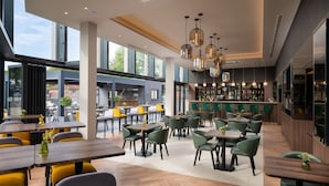 A modern restaurant with high ceilings, large windows, and a bar area.