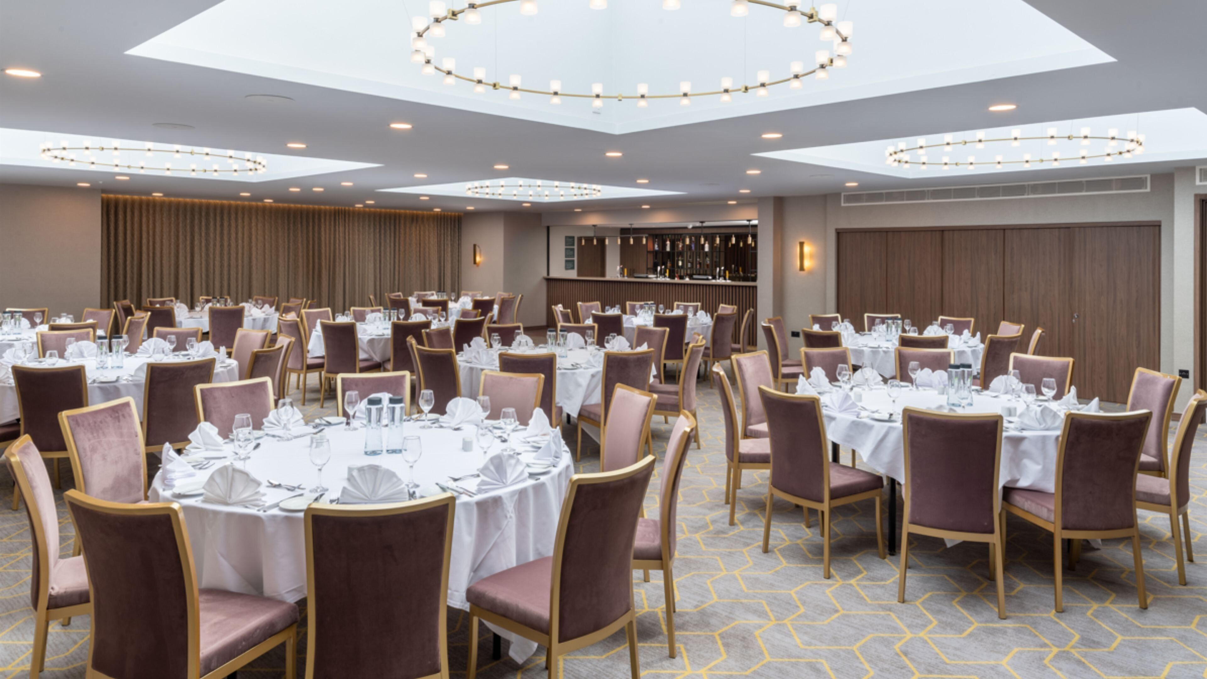 A banquet hall with round tables set for dining, equipped with chairs and table settings.