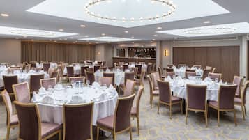A banquet hall with round tables set for dining, equipped with chairs and table settings.