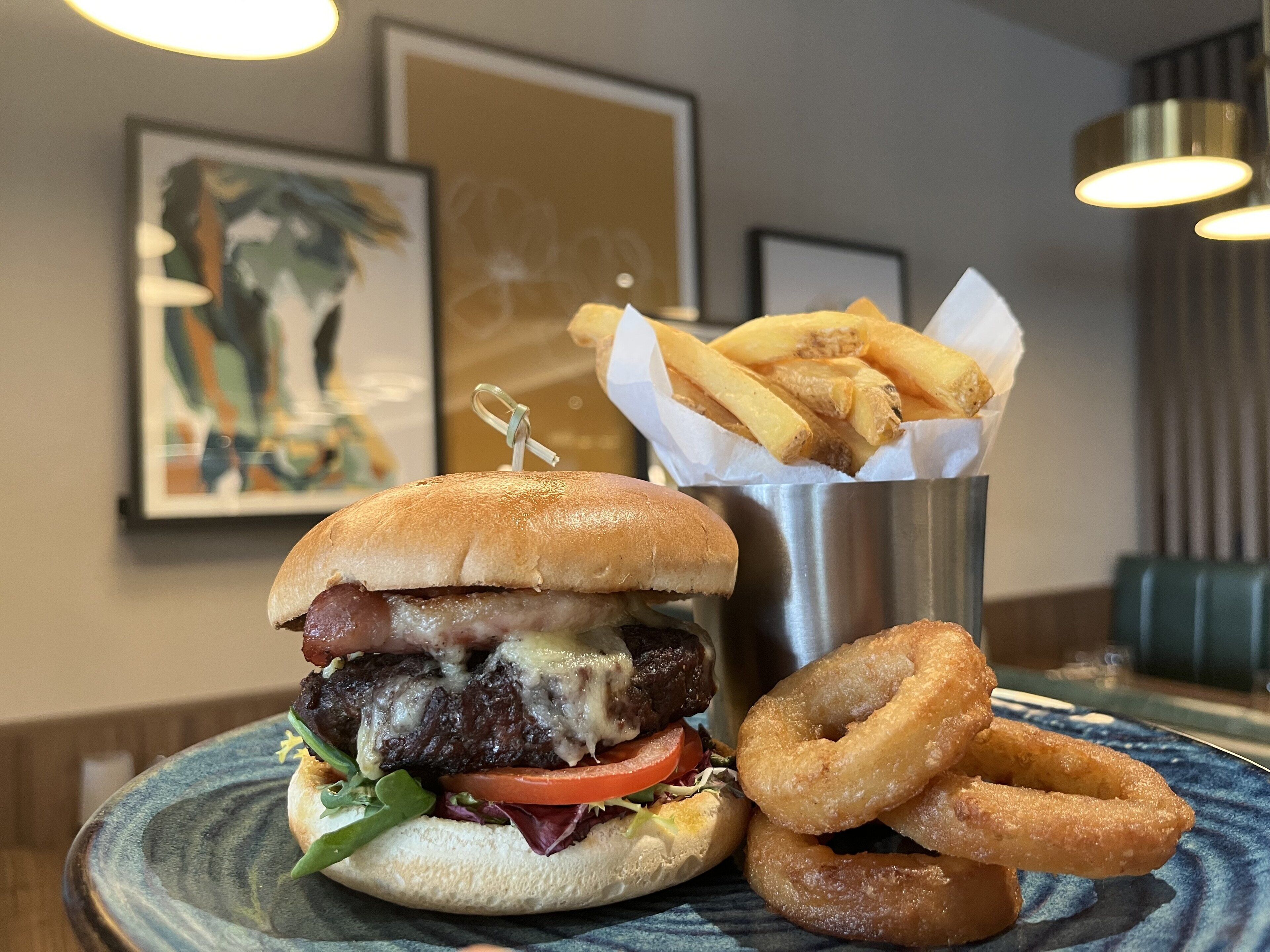 A burger with fries and onion rings on a plate.