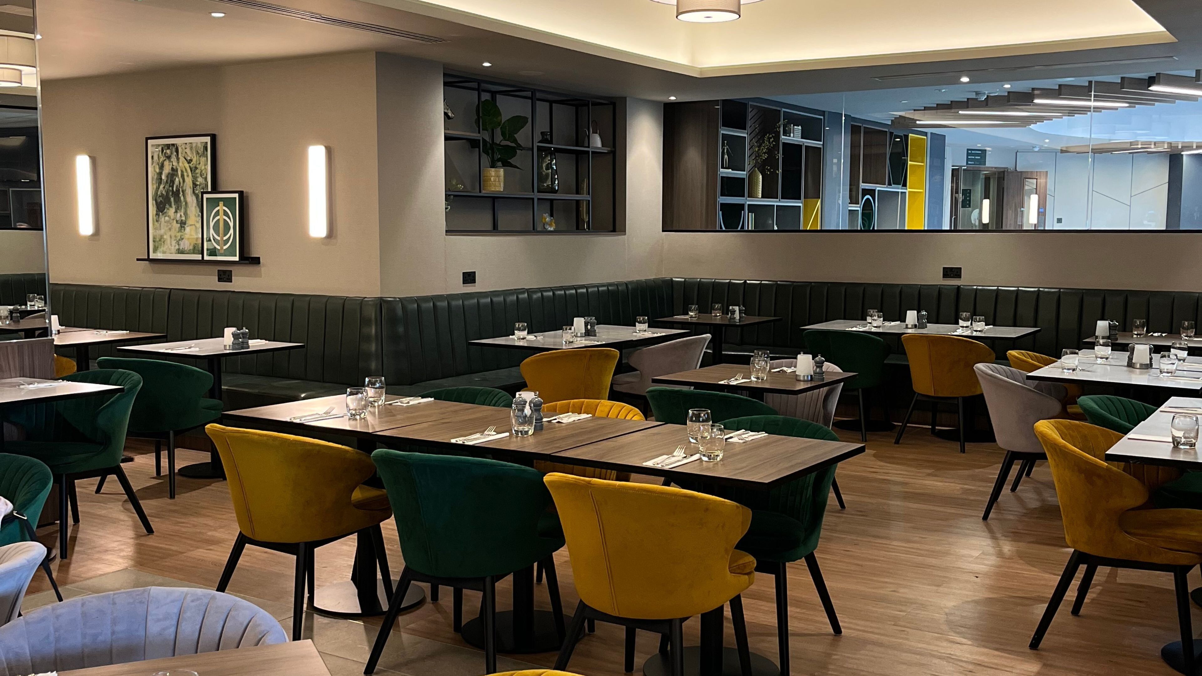 A restaurant with booths and tables, some with yellow chairs, and a modern interior design.