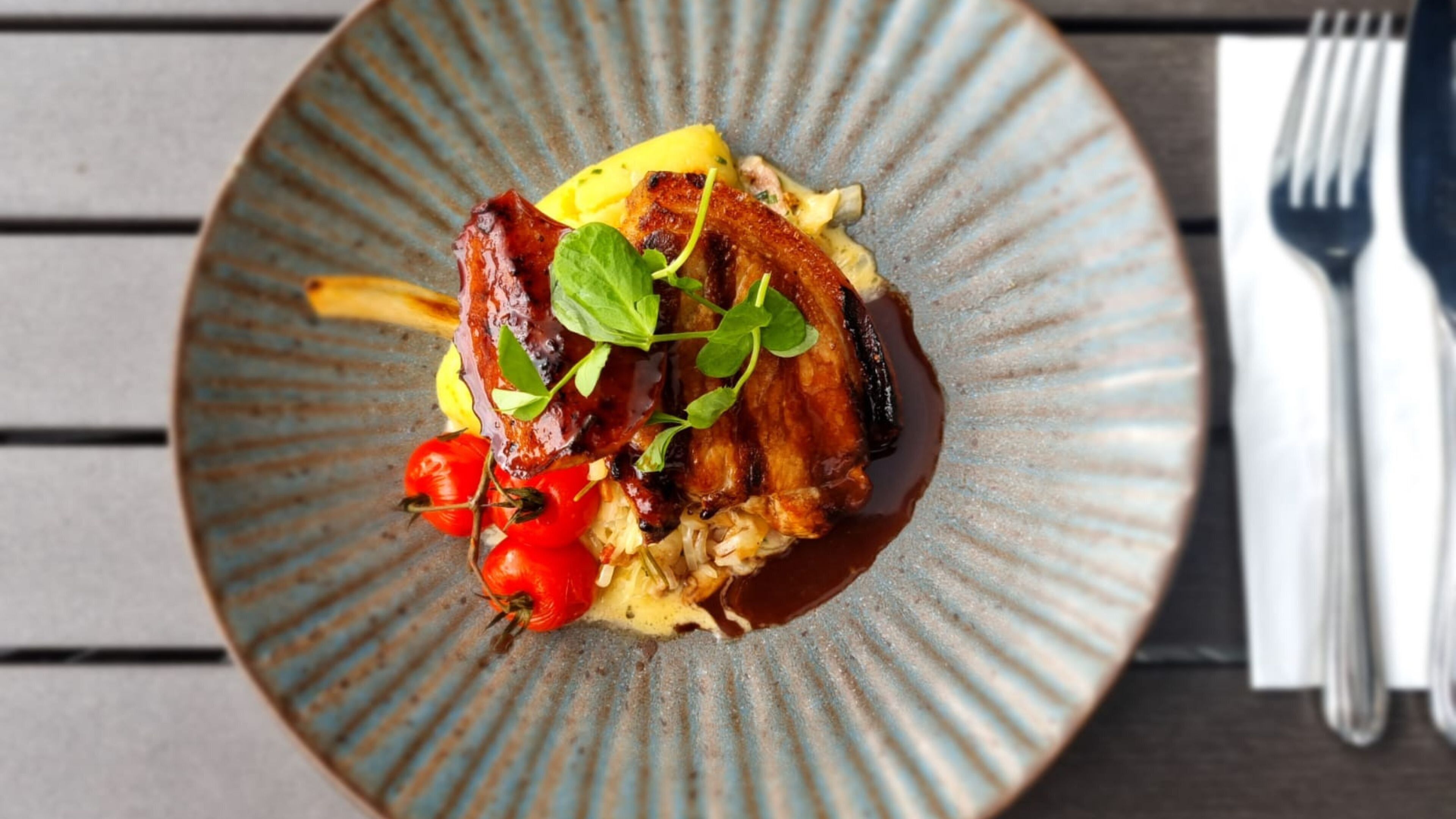 A plate of food with grilled meat, vegetables, and sauce.