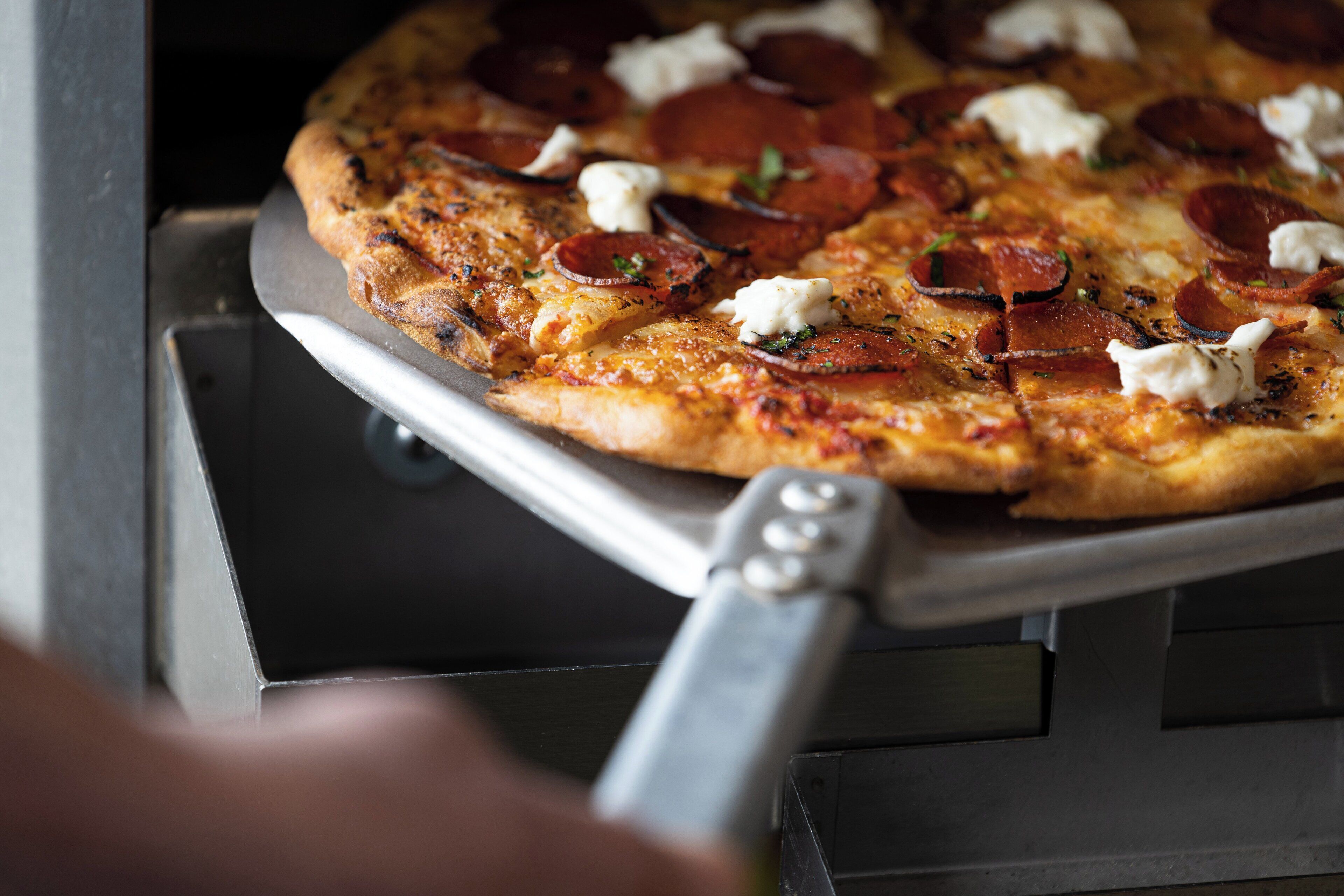 Eine Pizza mit Peperoni und Käse auf einem Tablett.