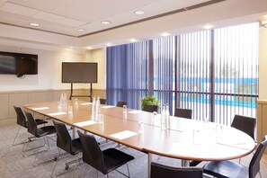 A conference room with a long table, chairs, a TV, and a large window with blinds. - lyf Chelsea London (London)