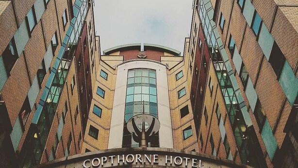 A symmetrical building with a central entrance and the text "COPTHORNE HOTEL" at the base.