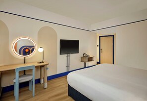 Une chambre d’hôtel avec un lit, un bureau et une chaise, une télévision et une porte.