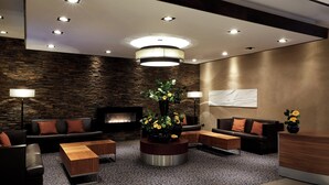 A modern lobby with a stone wall, a fireplace, a round coffee table, and a reception desk.