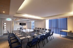 A conference room with a long table, chairs, a flat-screen TV, and a large window with blinds. - lyf Chelsea London (London)