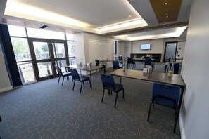 A conference room with tables, chairs, a large screen, and a view through the glass doors. - lyf Chelsea London (London)