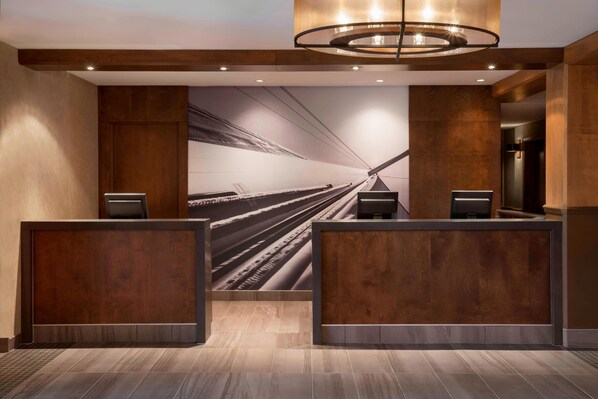 A reception area with a modern design, featuring a large wall mural of a train track, wooden reception desks, and a contemporary light fixture. - Residence Inn by Marriott Mont Tremblant Manoir Labelle (Mont-Tremblant)
