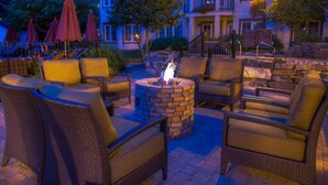 An outdoor seating area with wicker chairs and a central fire pit.