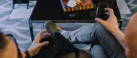 Una sala de estar acogedora con chimenea, una mesa de centro con aperitivos y dos personas relajándose.