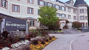 Entrada de un hotel con un letrero que dice 'Hotel Residence Inn by Marriott' y un jardín ajardinado con flores.