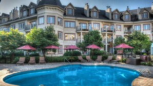 A large, multi-story building with a swimming pool, outdoor seating, and a well-maintained garden.