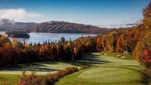A golf course with a lake and autumn foliage.