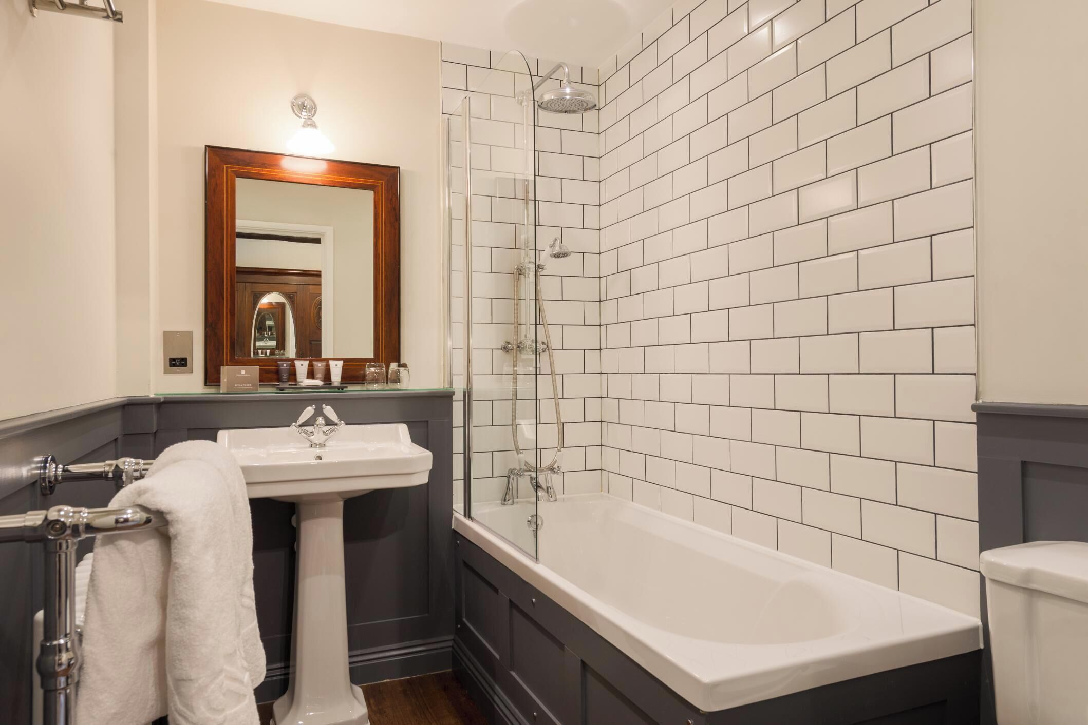 A bathroom with a white sink, a bathtub, a glass-enclosed shower, and a mirror with a wooden frame.