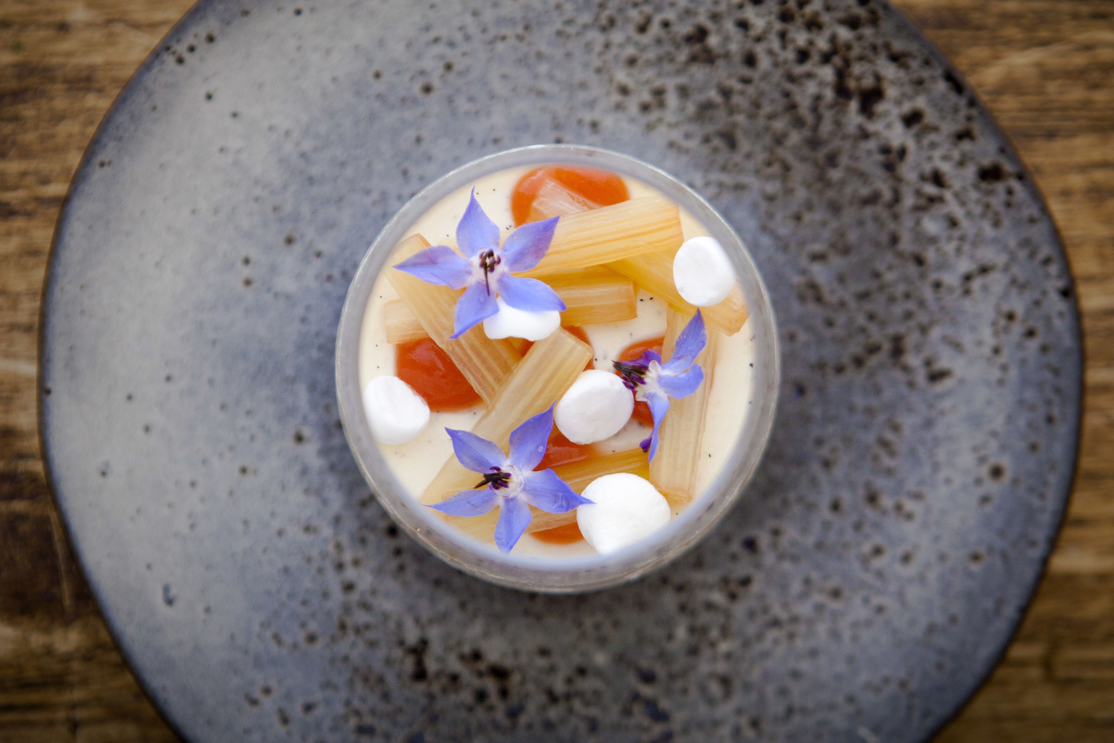A dessert in a clear glass bowl on a speckled ceramic plate.