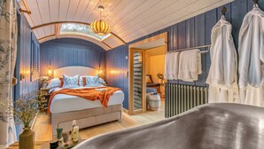 Un dormitorio con cama, mesita de noche, lámpara y vistas al exterior.