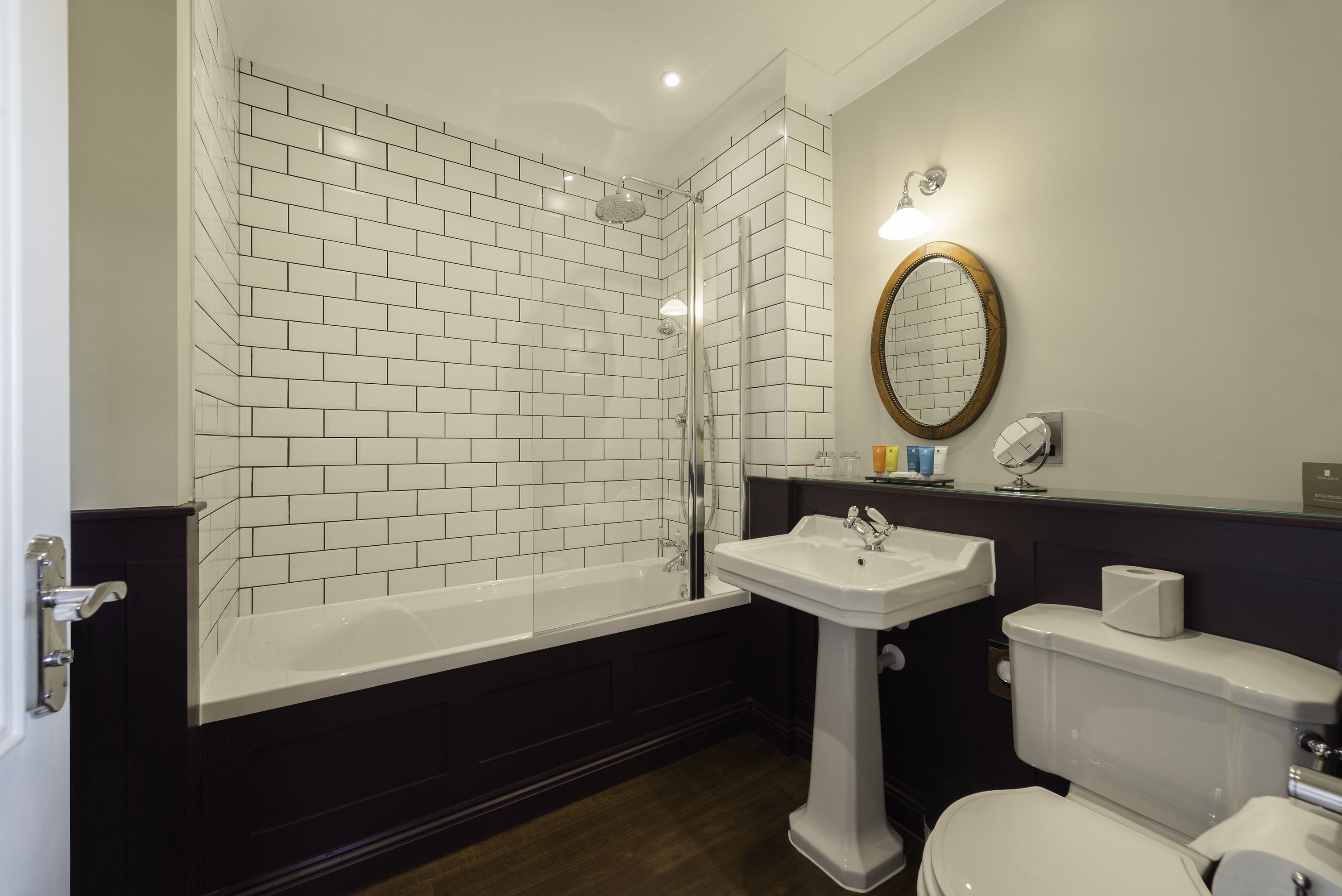 Un baño moderno con azulejos blancos tipo metro, una bañera independiente, un lavabo sobre pedestal y un inodoro.