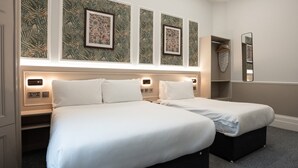 Habitació d'hotel amb dos llits, un armari, un mirall i obra d'art a les parets.