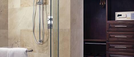 A modern bathroom with a glass-enclosed shower, marble tiles, a white towel, and a dark wooden vanity with drawers.