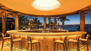 Eine Bar mit einer Holztheke, Barhocker und Regalen mit Flaschen.