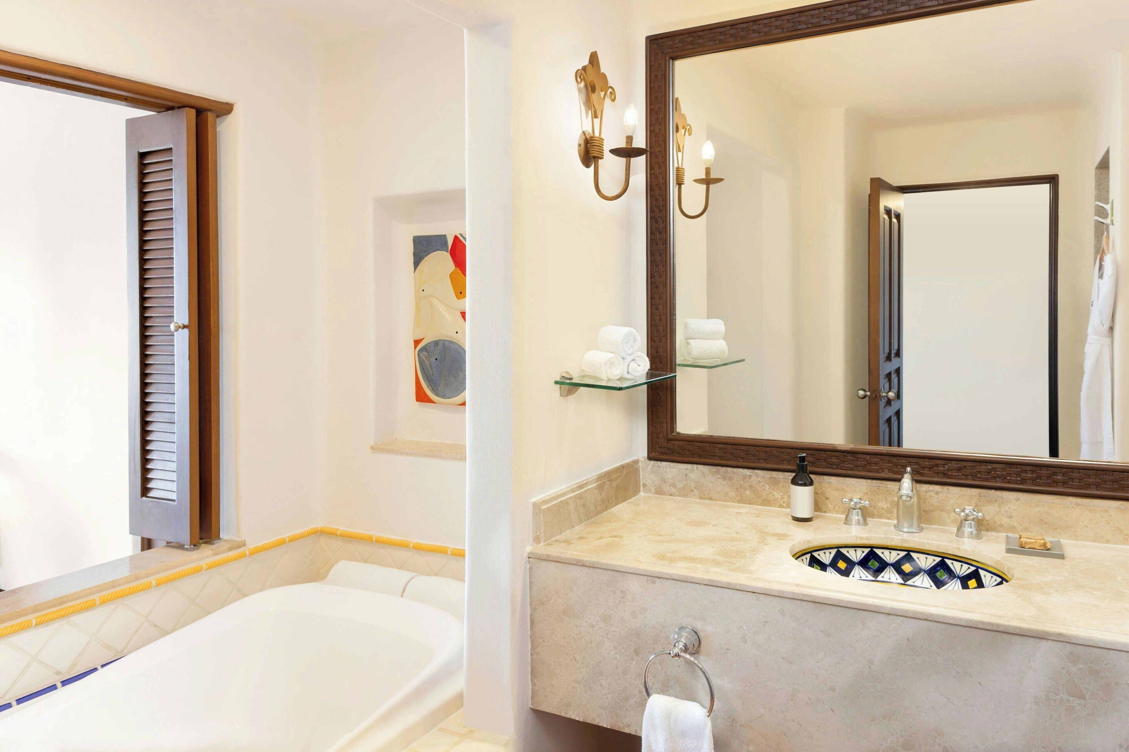 A bathroom with a bathtub, a sink with a mirror, and a towel rack.