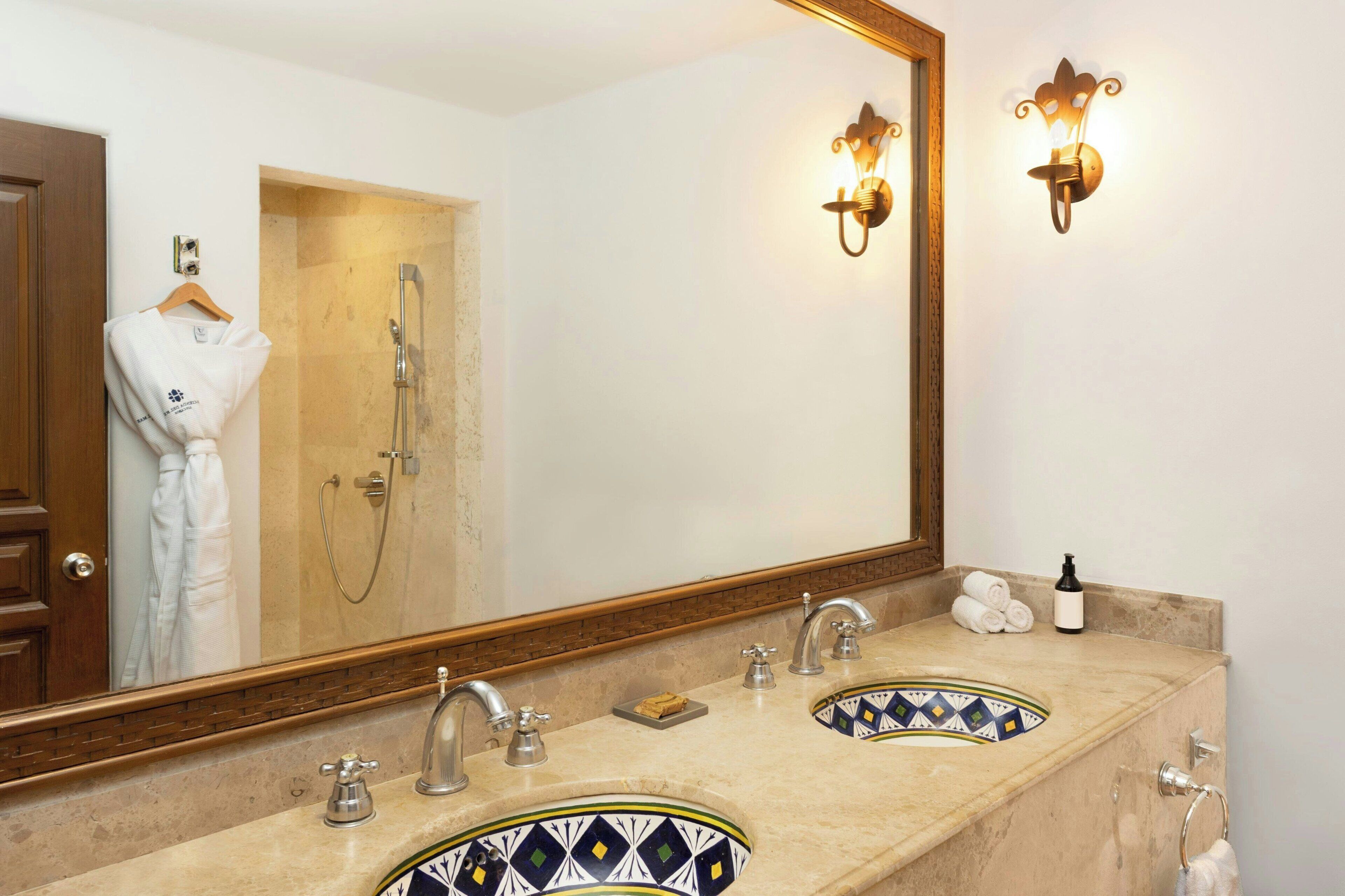A bathroom with two sinks, a large mirror, and a shower.