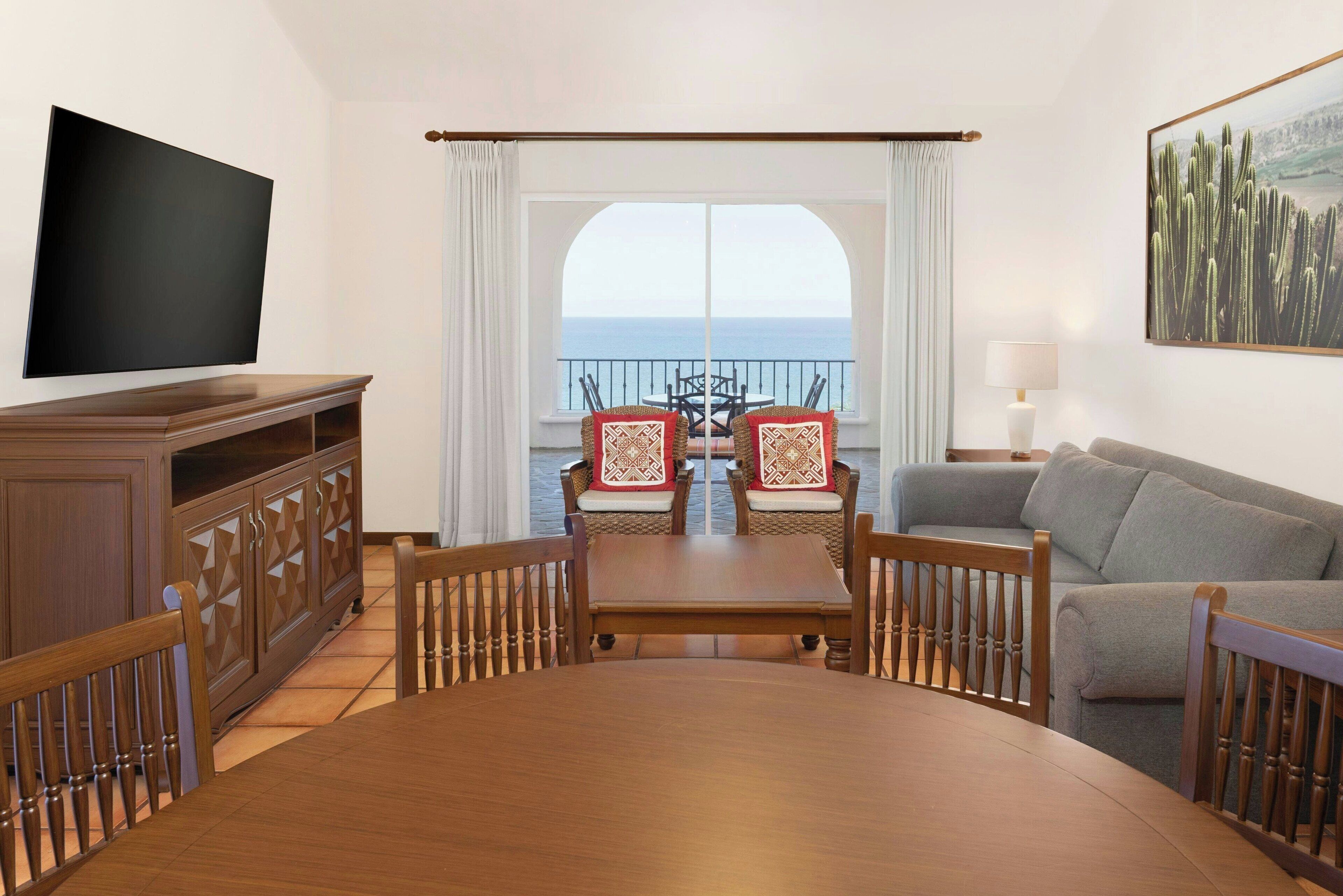 Una sala de estar con televisor, una mesa de comedor y un sofá.