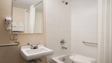 A bathroom with a sink, mirror, shower, and a small stool.